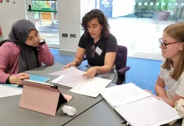 Arij Asad working through mathematics with students around a table